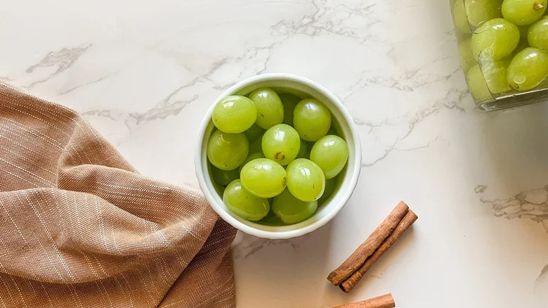 Sweet Pickled Grapes in white bowl on counter with cinnamon stick