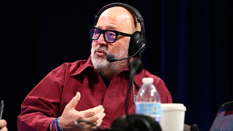 The chef Andrew Zimmern, wearing a red shirt and a microphone headset, in conversation