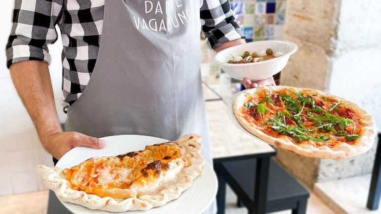 Waiter holding a pizza and calzone