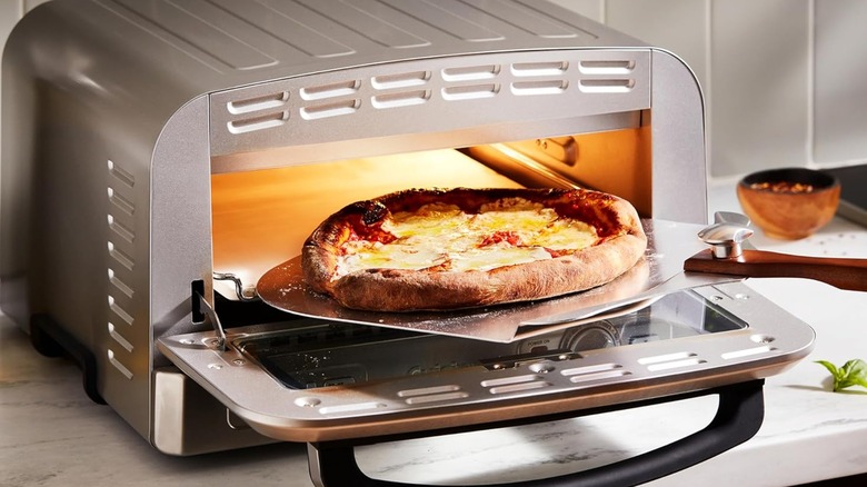 A Cuisinart indoor pizza oven with a cooked pizza