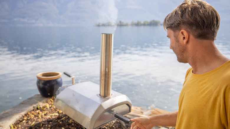 A man using a pizza stone by a lake