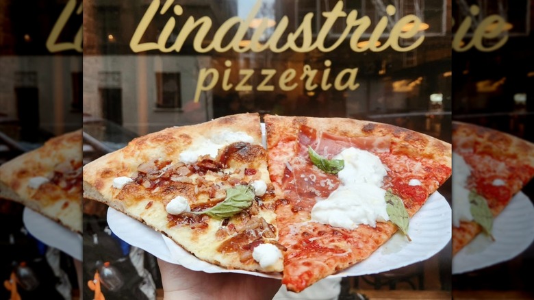 customer holding L'Industrie pizza slices