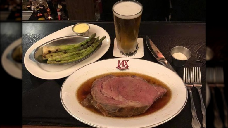 Prime rib with side plate of asparagus, beer, and utensils