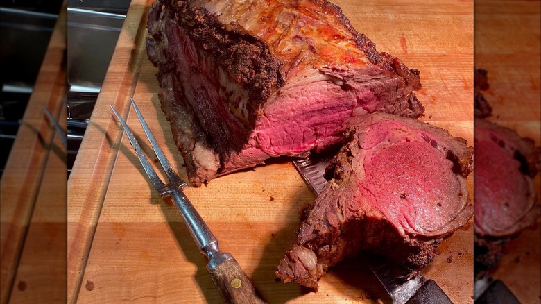 Prime rib being sliced on wooden board