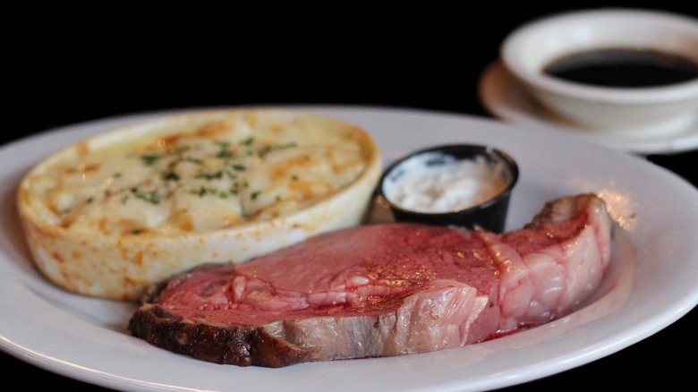 Prime rib on plate with dish of potatoes and horseradish