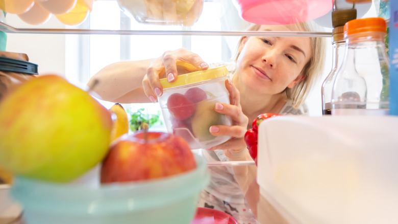 A woman opening a container with produce