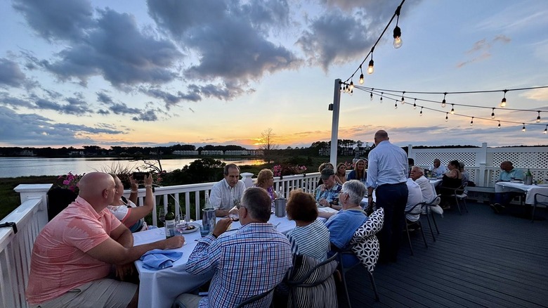 people having dinner on the deck with views of the water