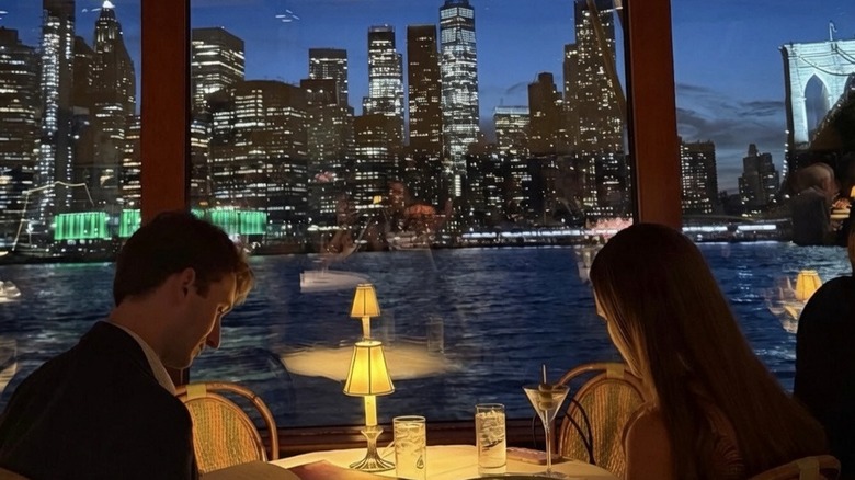 Diners reading the menu at the River Cafe in front of a view of Manhattan