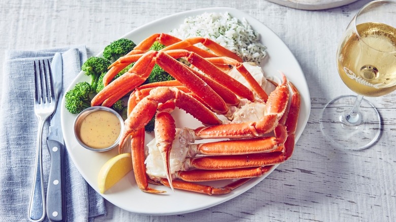crab legs on white plate served with white wine