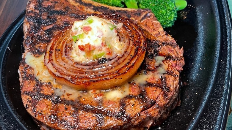 steak topped with butter and onions on plate