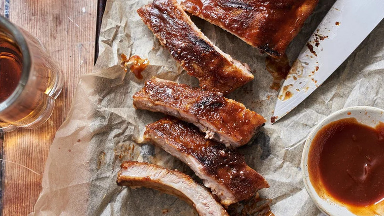 Cider and Chili-Glazed Baby Back Ribs on parchment paper with bowl of sauce