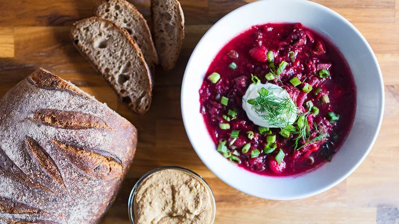 Short Rib Borscht in a white bowl with a loaf of bread