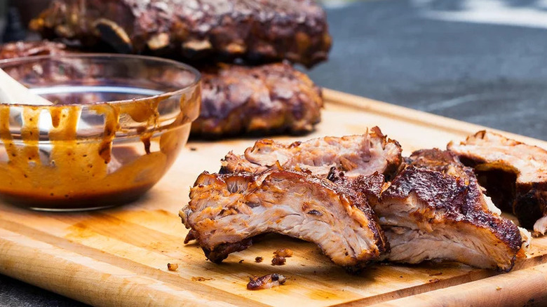 Sous-Vide Barbecue Ribs on wooden cutting board with sauce in bowl