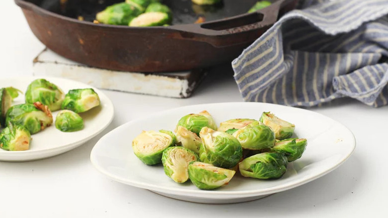Sauteed sprouts served from skillet onto white plate