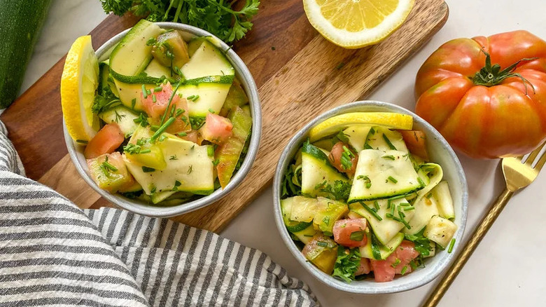 Herby zucchini ribbon and tomato salad in two bowls, garnished with chopped chives