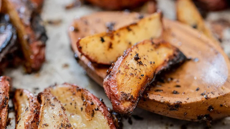 Close up of roasted potato wedges resting on wooden spoon