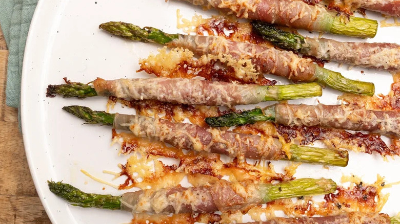 Cheesy prosciutto-wrapped roasted asparagus spears on plate