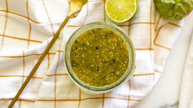 Fresh Tomatillo Salsa Verde in small glass jar on towel