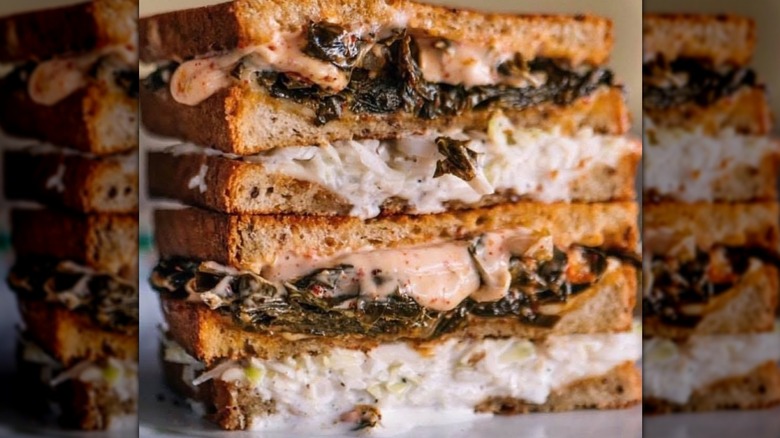 Collard greens sandwich stuffed with coleslaw and dripping with cheese and Thousand Island dressing, halved and stacked