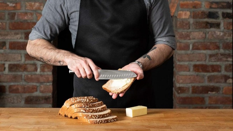 A person spreading butter with a Babish santoku knife