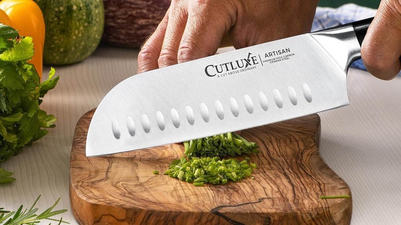 A person cutting with a Cutluxe santoku knife