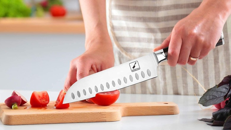 A person cutting a tomato with an Imarku santoku knife
