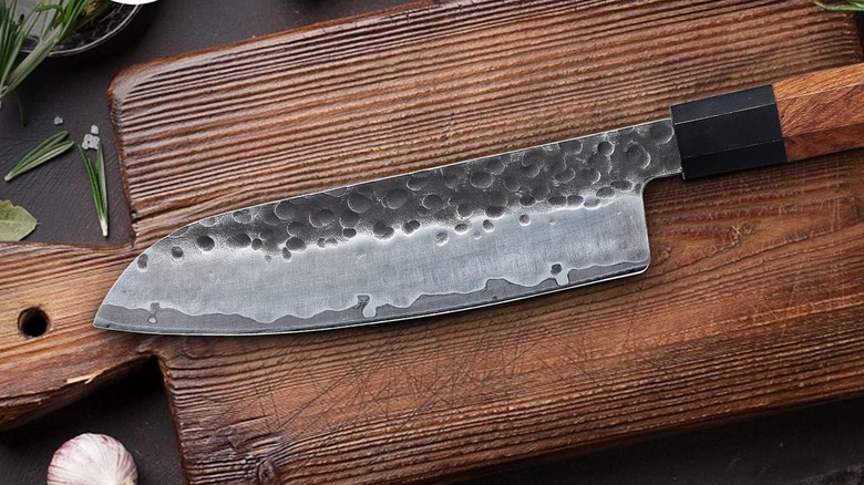 A Mitsumoto santoku knife on a wooden cutting board