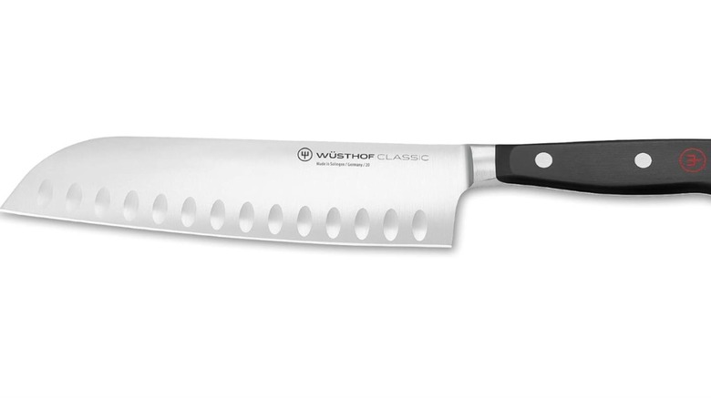 A Wüsthof santoku knife placed vertically on a white background