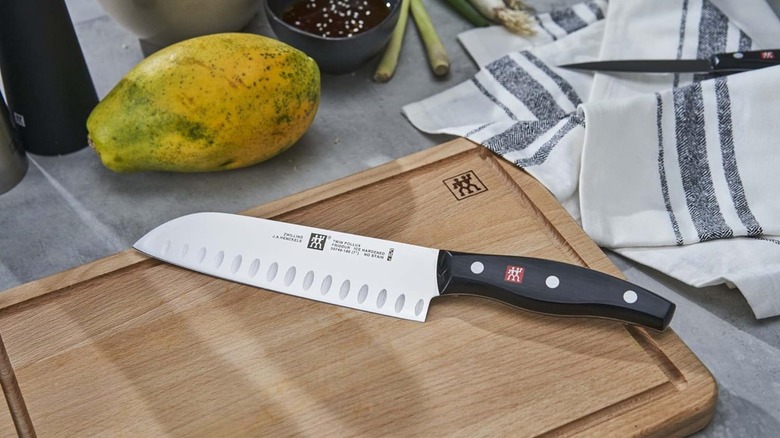 A Zwilling santoku knife on a wooden cutting board