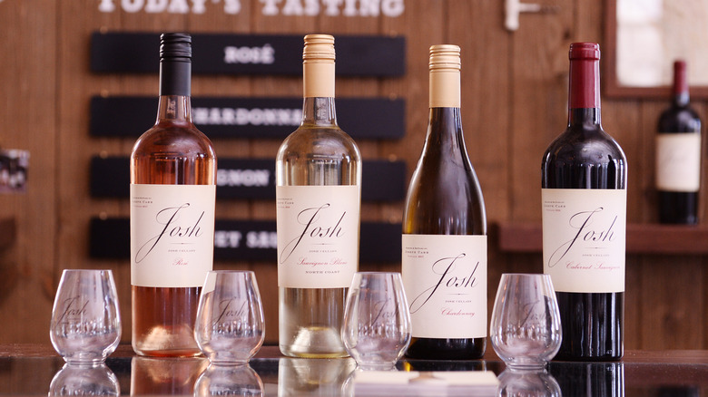Four bottles of Josh Cellars wine with glasses laid out on a table in a tasting room