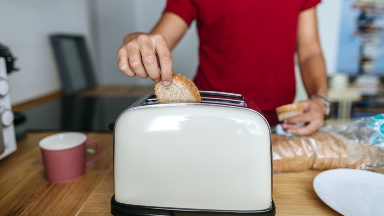 A person removing toast from the toaster