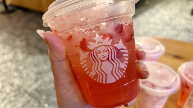 close up of woman holding Starbucks Strawberry Acai Lemonade Refresher in hand