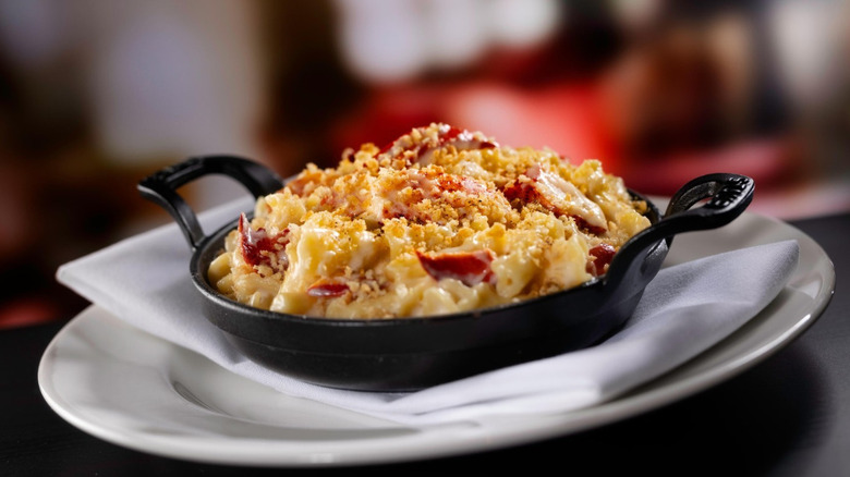 Lobster mac and cheese in a cast-iron skillet resting on top of a white cloth napkin on a white plate