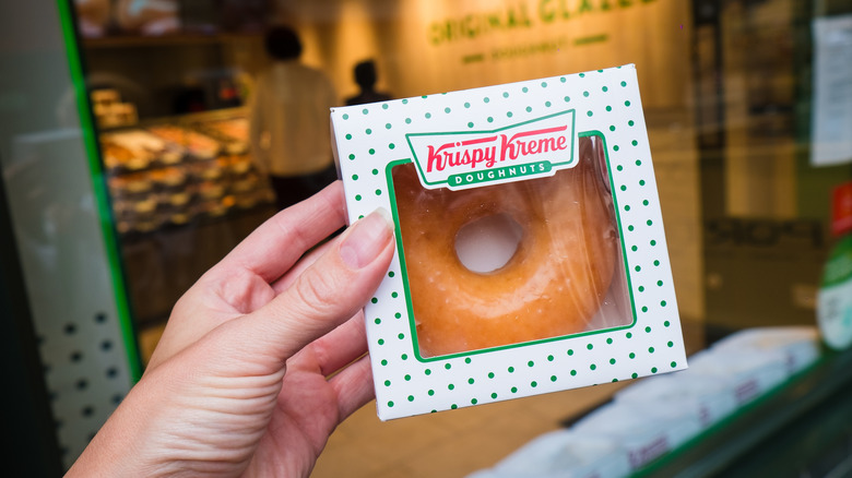 Person holding Krispy Kreme donut in a box