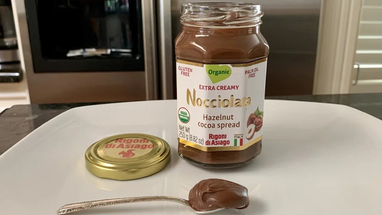 An open jar of Nocciolata spread with a spoonful