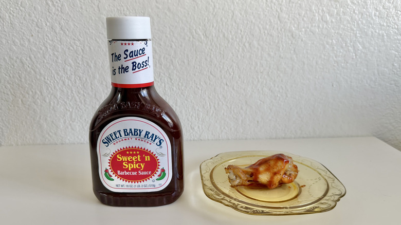 Sweet Baby Ray's Sweet 'n' Spicy BBQ Sauce on table beside chicken leg