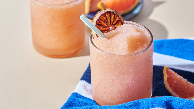 Negroni slushie in glass with dried orange slice and straw