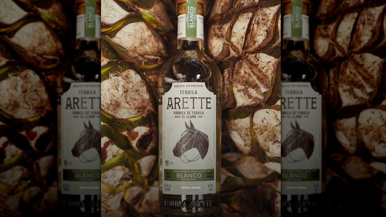 A bottle of Arette Artesanal Blanco on a bed of pinas