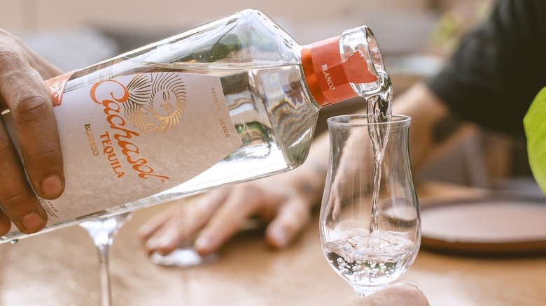 A hand pouring a bottle of Cachasol