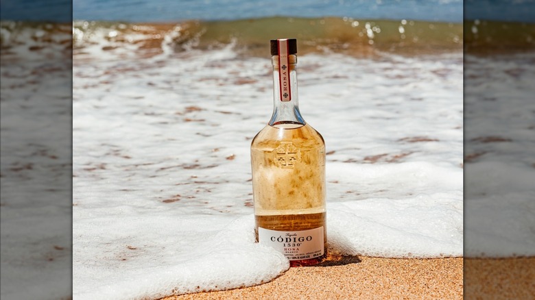 A bottle of Código 1530 Rosa in the surf