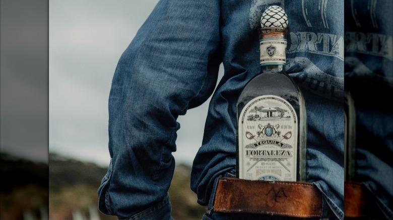 A bottle of blanco in a jimador's waistband