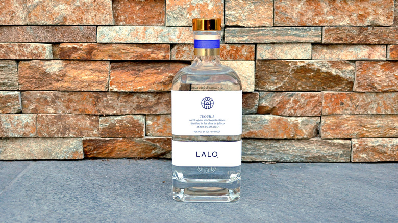 Bottle of Lalo in front of stone wall