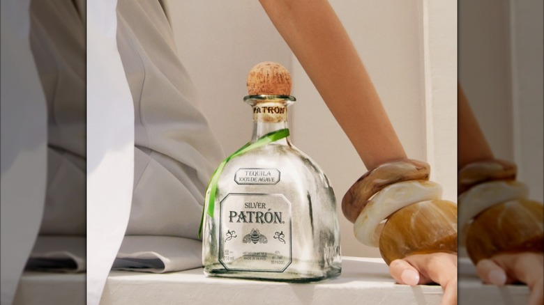 A woman leaning over a bottle of Patrón