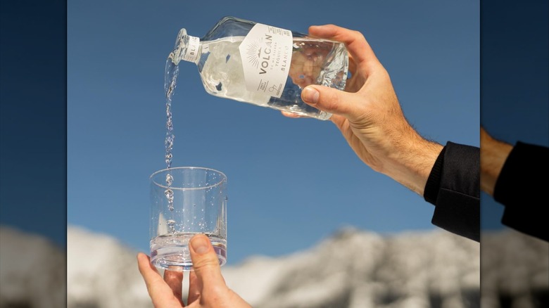 A hand pouring a bottle of Volcan blanco into a glass