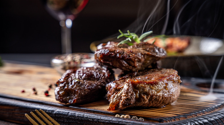 steaks piled on top of each other with wine glass at steakhouse