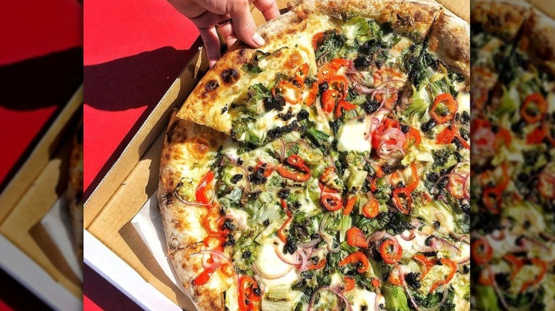Person picking up pizza slice
