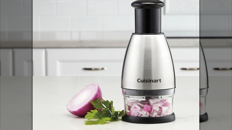A Cuisinart chopper on a counter with red onions