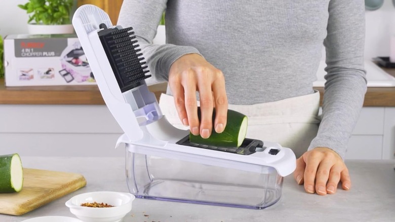 A person cutting a cucumber with a Fullstar vegetable chopper