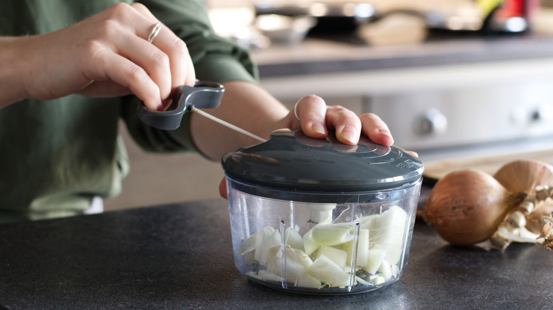 A person pulling the lever for a manual food processor