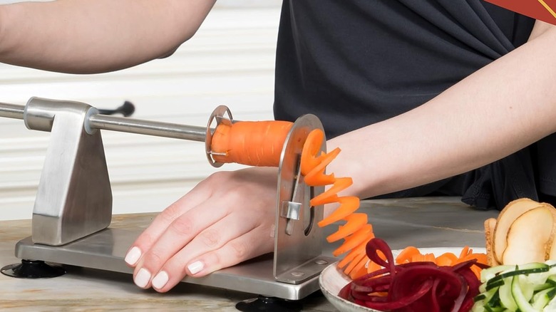A person cutting a carrot with the Homarden veggie spiralizer